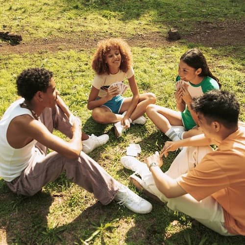 Group of friends enjoying picnic in a public park, using phone to check social media

