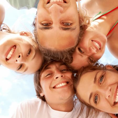 Below view of joyful teens looking at camera with smiles on vacation